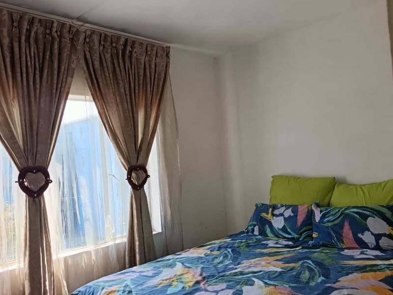A standard bedroom featuring a window with curtains and a central ceiling light fixture.