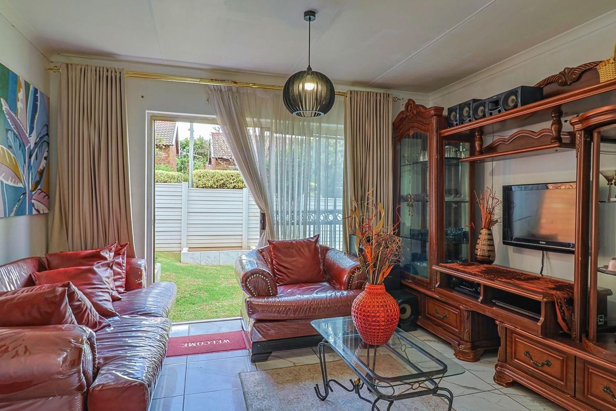 A living room featuring tiled flooring and a sliding glass door providing direct access to the rear garden area.