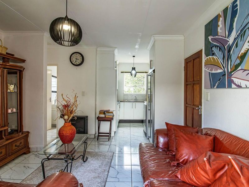 Open plan living area featuring tiled flooring and a functional kitchen with built-in cabinetry, providing a seamless flow between the living and cooking spaces.
