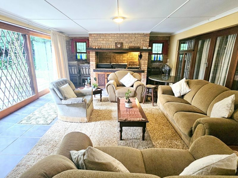 Spacious living room featuring a built-in brick fireplace, tiled flooring, and large sliding glass doors providing access to the outdoor area.
