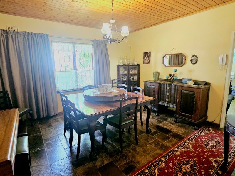 A dining room featuring a timber-clad ceiling, stone-look floor tiles, and a central chandelier, offering a traditional aesthetic.