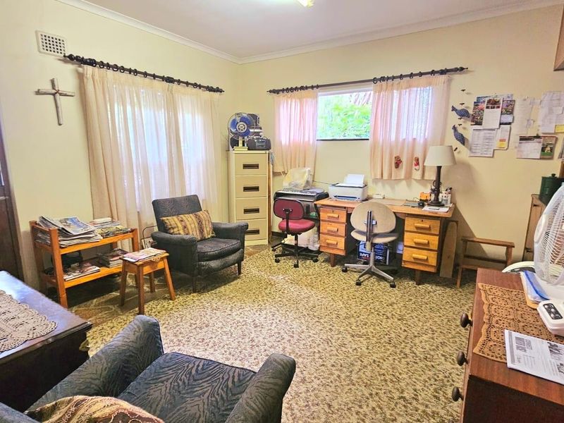 A functional home office space featuring built-in shelving, carpet flooring, and direct access to the exterior via a security gate.