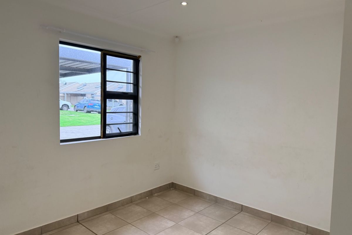 A vacant bedroom featuring neutral tiled flooring, a window with security bars, and recessed lighting, offering a clean canvas for personalization.