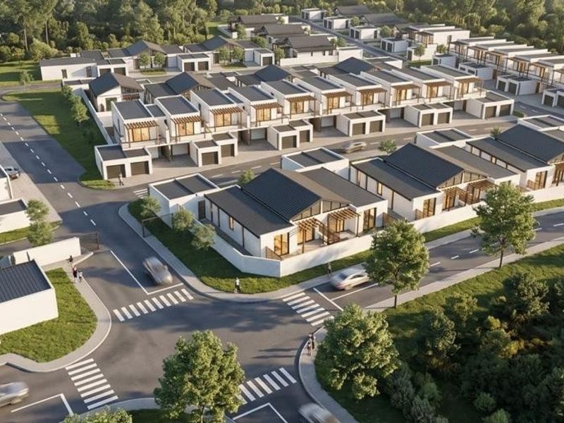 An aerial view of a modern residential estate featuring uniform housing units, paved streets, and landscaped surroundings.