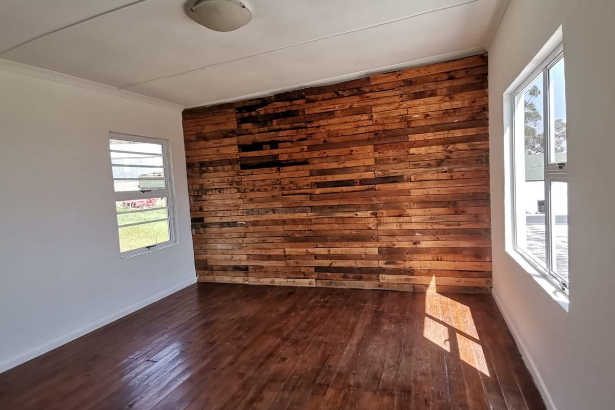 An empty bedroom featuring timber flooring and a rustic timber-clad feature wall, providing a blank canvas for interior design.