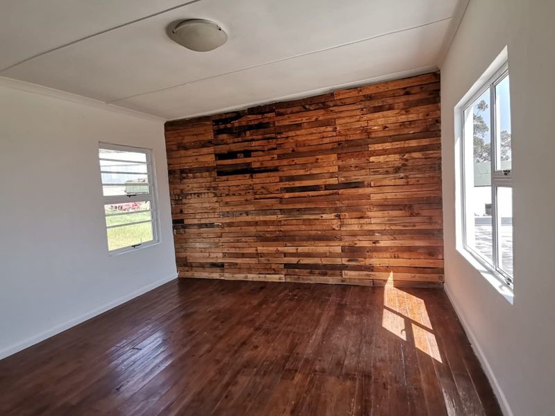 An empty bedroom featuring timber flooring and a rustic timber-clad feature wall, providing a blank canvas for interior design.