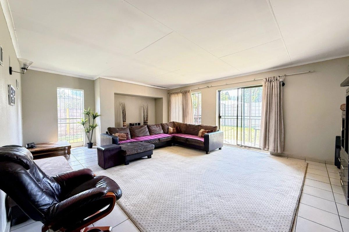 Spacious living room featuring tiled flooring, a recessed wall niche, and large sliding glass doors providing access to the rear garden area.