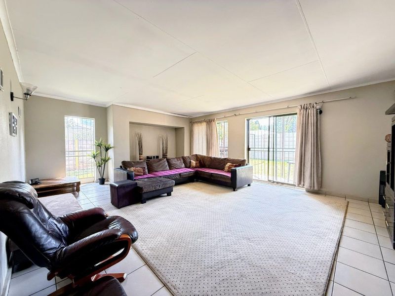 Spacious living room featuring tiled flooring, a recessed wall niche, and large sliding glass doors providing access to the rear garden area.