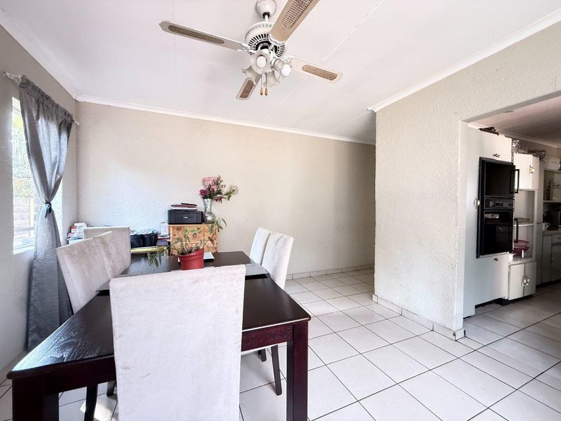 Open plan dining area featuring tiled flooring, a ceiling fan, and a view into the adjacent kitchen with built-in oven.