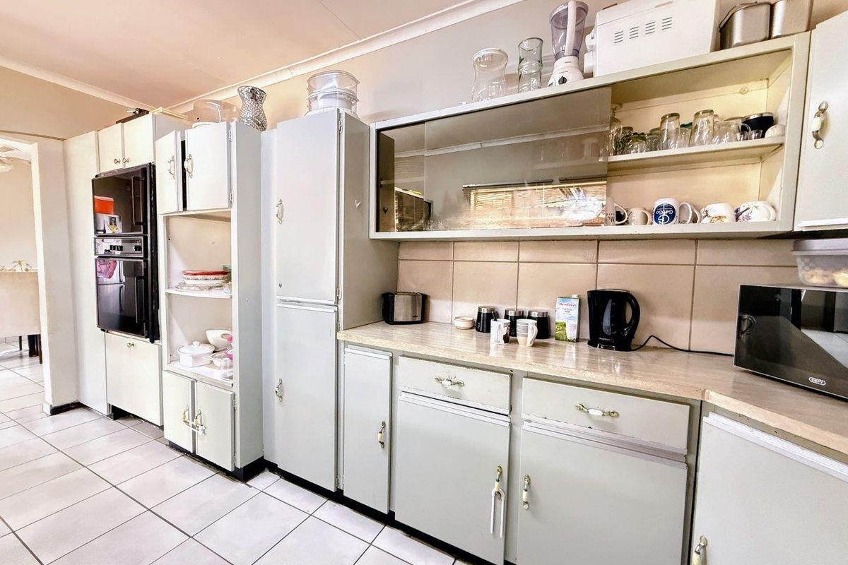 A dated kitchen featuring built-in cabinetry, tiled flooring, and a tiled backsplash, offering significant potential for a modern renovation.
