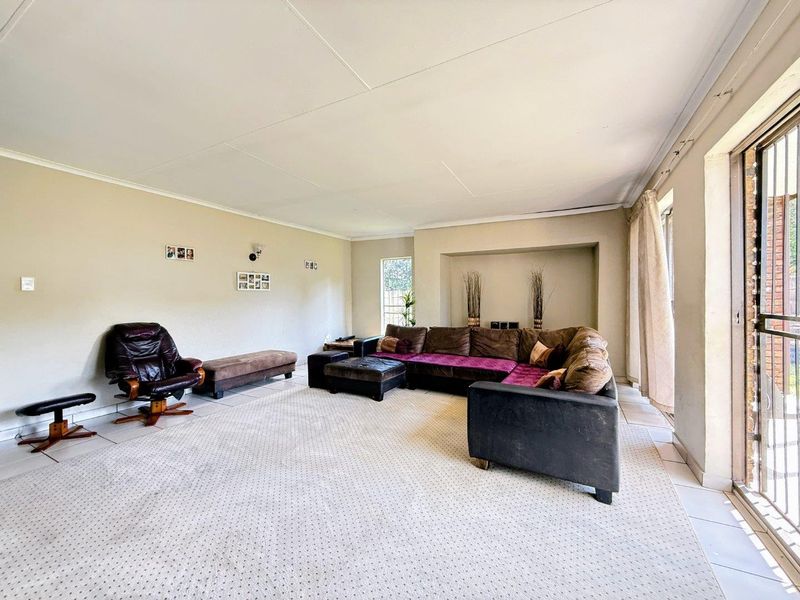 Spacious living room featuring tiled flooring, a recessed wall niche, and large sliding glass doors providing access to the outdoor area.