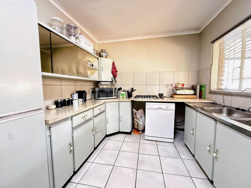 Functional kitchen featuring laminate countertops, built-in cabinetry, a gas hob, and tiled flooring, offering a practical layout with potential for modern updates.