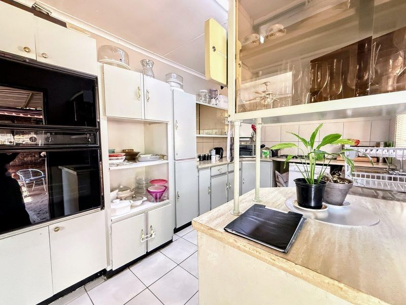 A dated kitchen featuring built-in cabinetry, tiled flooring, and a built-in oven, offering potential for a modern renovation.
