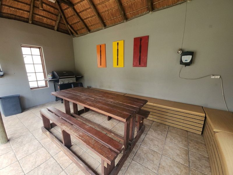 Covered outdoor patio area featuring a thatched roof, tiled flooring, and built-in bench seating, ideal for relaxed outdoor dining and entertainment.
