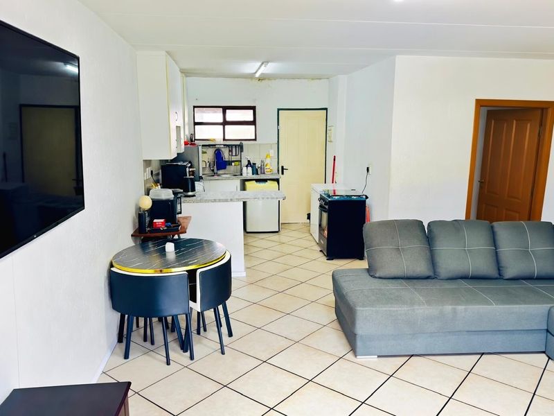 Open-plan living and kitchen area featuring tiled flooring, functional cabinetry, and a built-in stove, offering a practical layout for daily living.