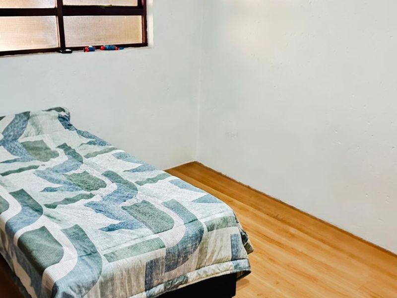 A simple bedroom featuring laminate flooring and a window, providing a neutral space ready for personalization.