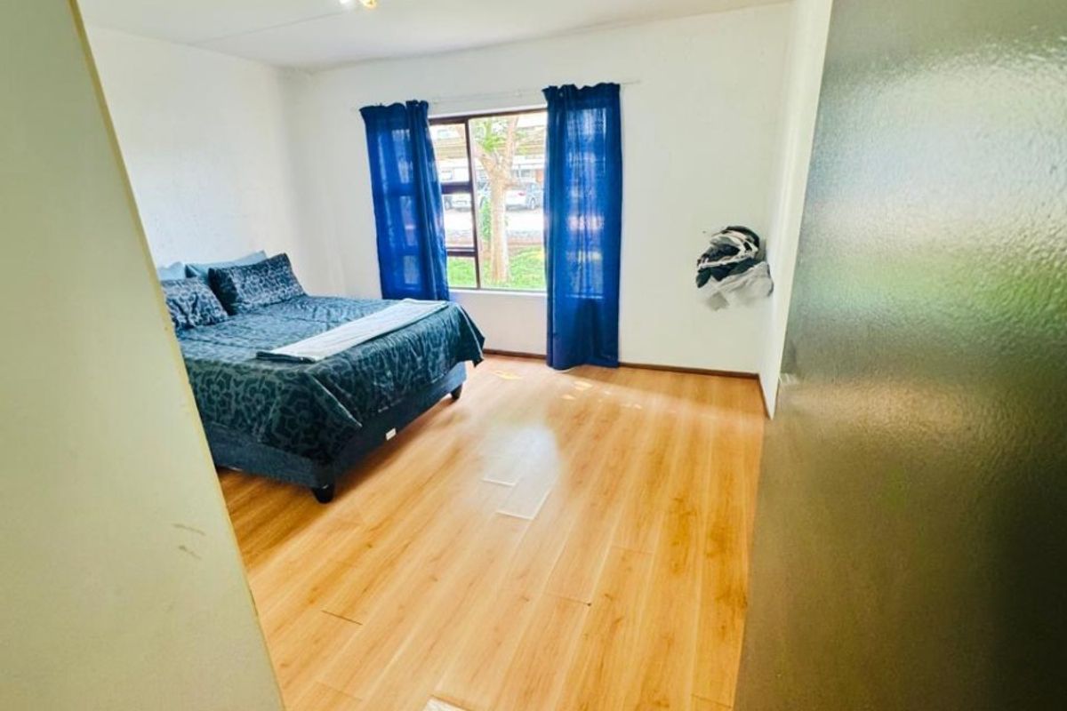 A bedroom featuring light-toned laminate flooring and a central ceiling light fixture, offering a clean and functional living space.