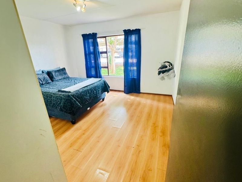 A bedroom featuring light-toned laminate flooring and a central ceiling light fixture, offering a clean and functional living space.