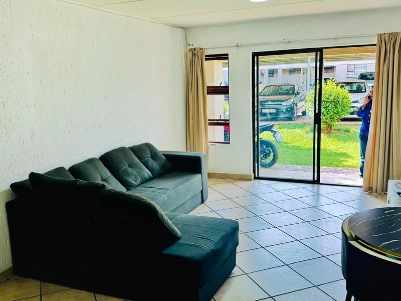 A living room featuring tiled flooring and a sliding glass door providing direct access to the exterior garden area.