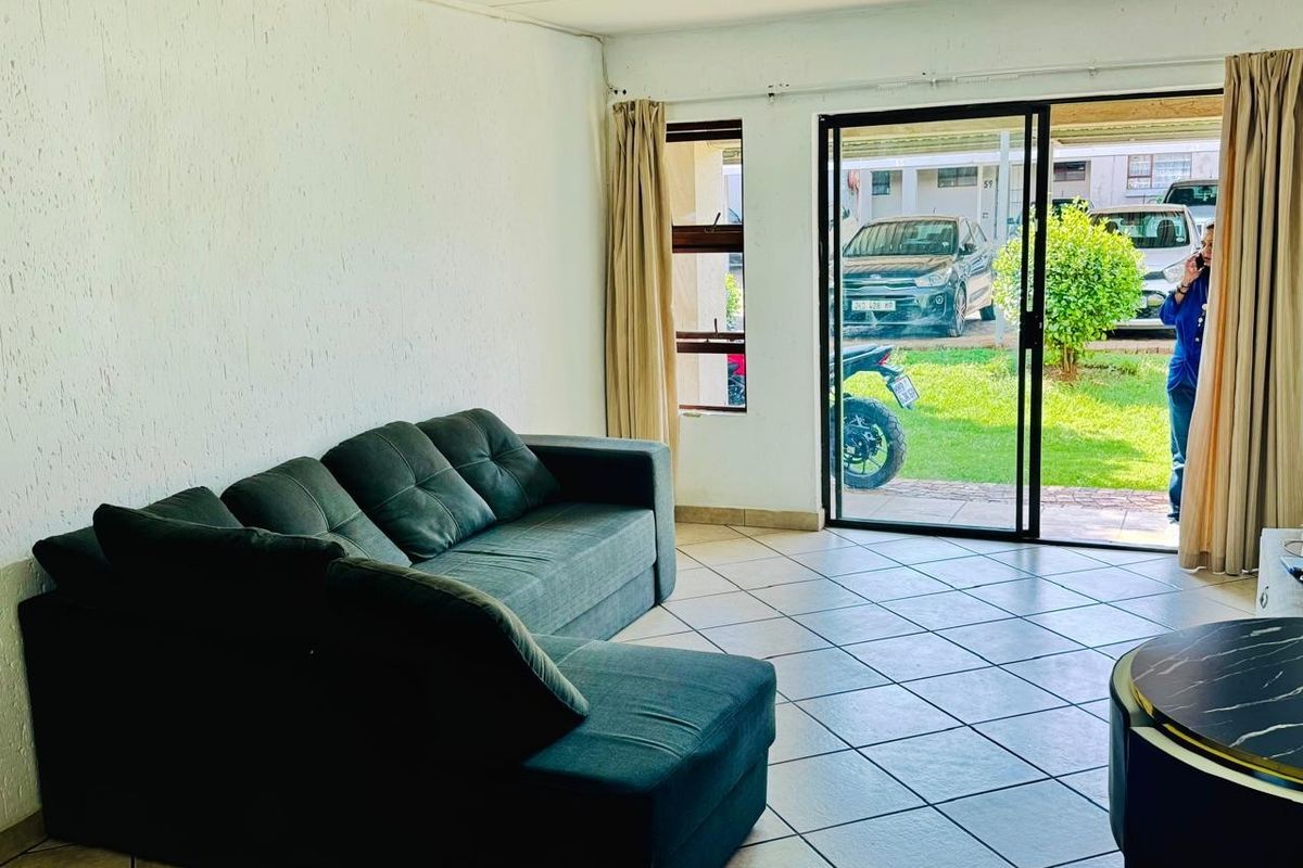 A living room featuring tiled flooring and a sliding glass door providing direct access to the exterior garden area.