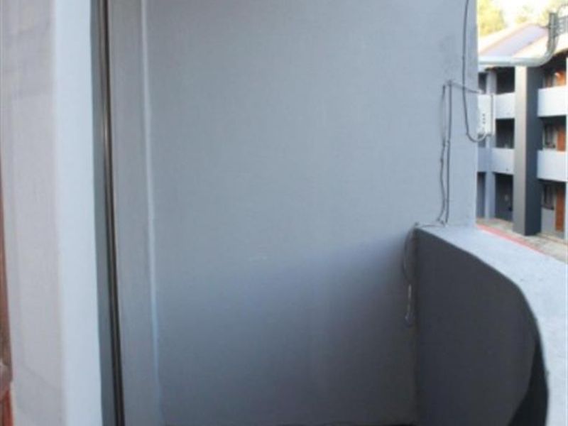 A compact apartment balcony featuring tiled flooring and a wall-mounted light fixture, offering a functional outdoor space.