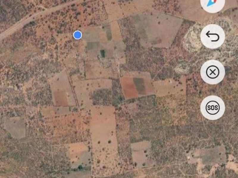 An aerial satellite view of a large rural farm property showing various plots of land and natural terrain.