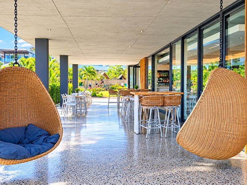 A spacious covered patio featuring polished terrazzo flooring, recessed lighting, and modern sliding glass doors, offering a seamless transition to the outdoor garden area.