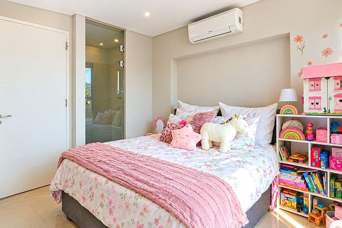 A well-maintained bedroom featuring tiled flooring, recessed lighting, and a wall-mounted air conditioning unit, with an adjacent glass-paneled door.