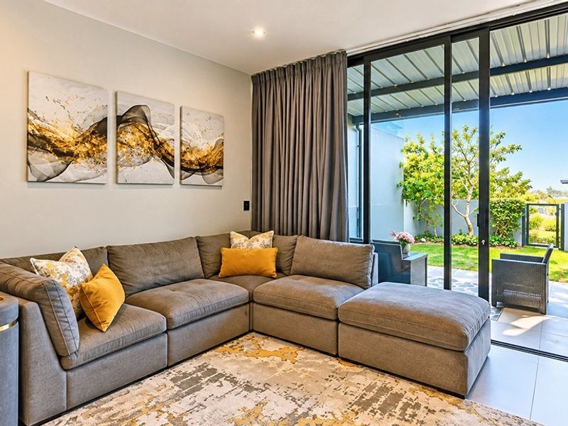 A bright living room featuring large sliding glass doors that provide seamless access to the outdoor patio and garden area.