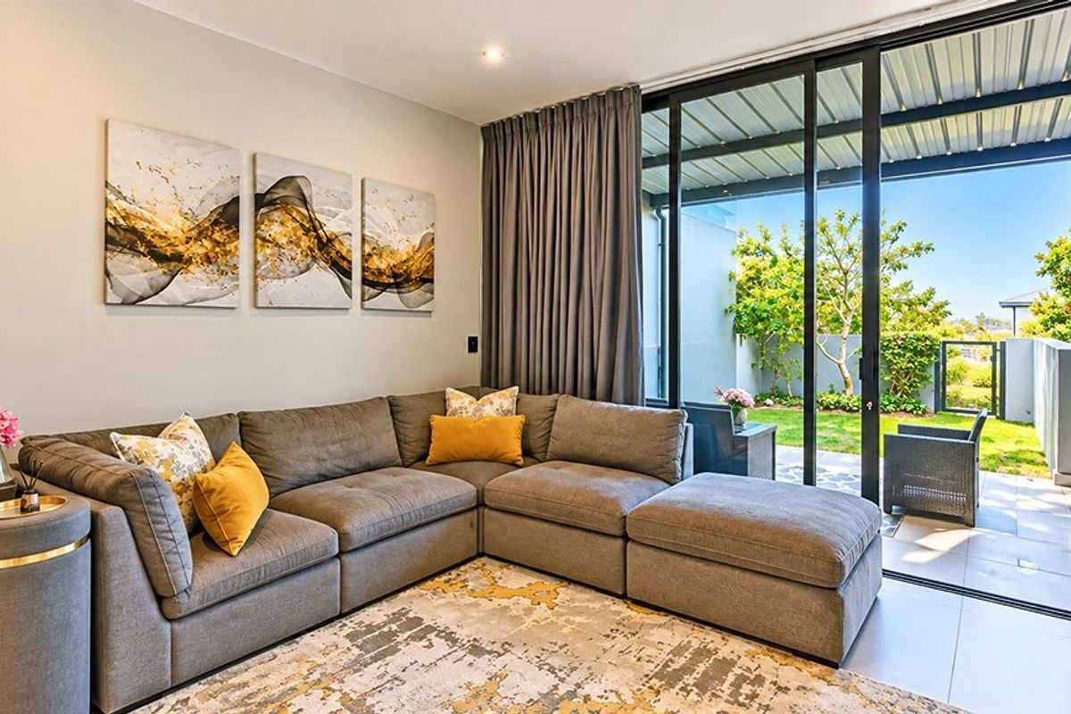 A bright living room featuring large sliding glass doors that provide seamless access to the outdoor patio and garden area.
