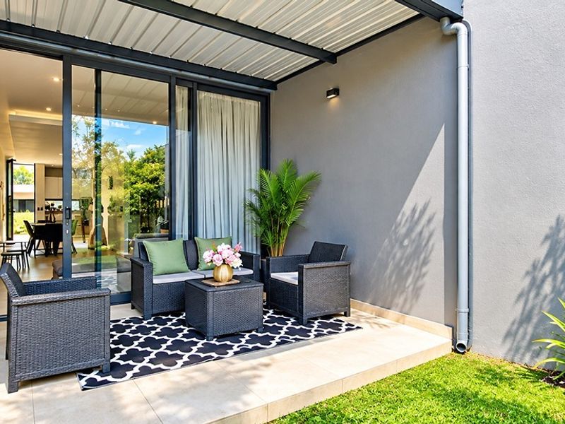 A modern covered patio featuring tiled flooring, sliding glass doors providing access to the interior, and a clean, well-maintained exterior wall finish.