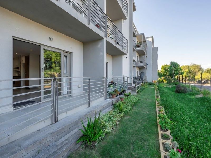 Ground floor patio featuring tiled flooring, metal balustrades, and direct access to a landscaped garden area with a retaining wall border.