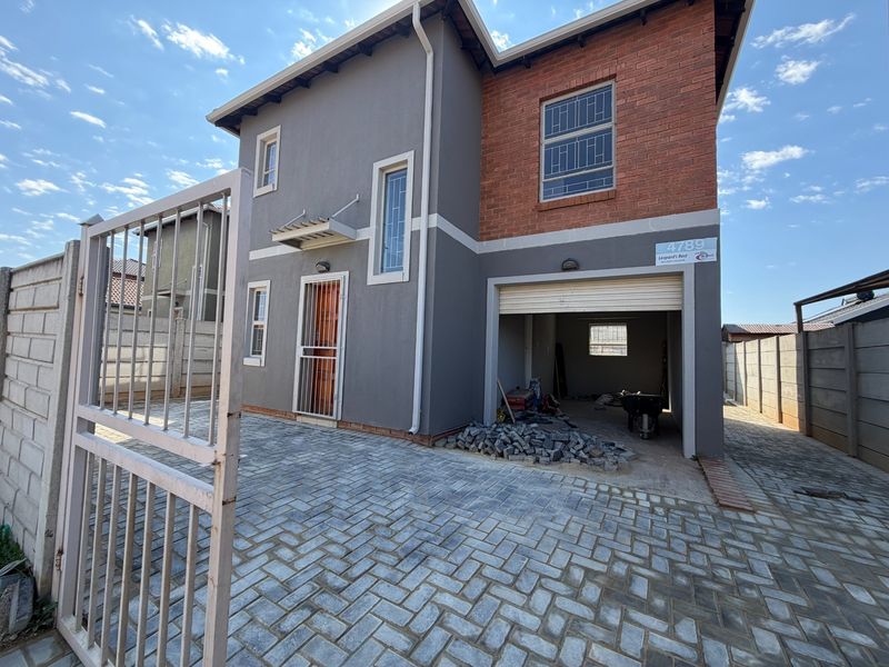 Front elevation of a two-story house featuring a paved driveway, integrated garage, and a combination of brick and plastered exterior finishes.