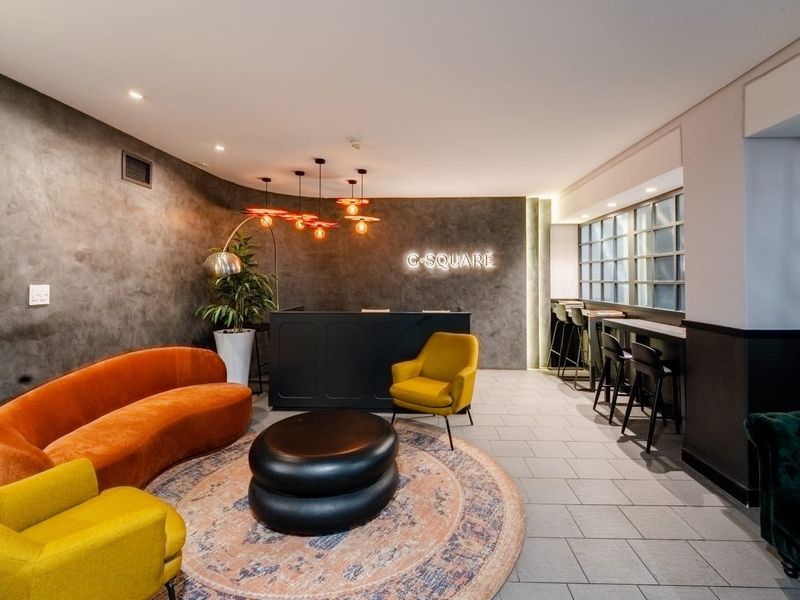 Modern clubhouse area featuring a reception desk, built-in bar counter, stylish feature wall, and contemporary tiled flooring.