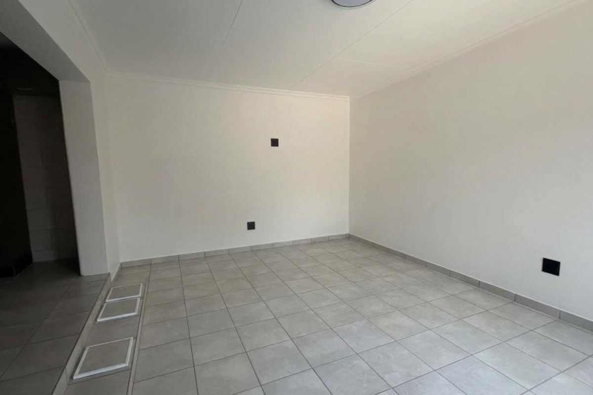 A clean, empty living area featuring neutral tiled flooring and white walls, providing a versatile blank canvas for interior design.
