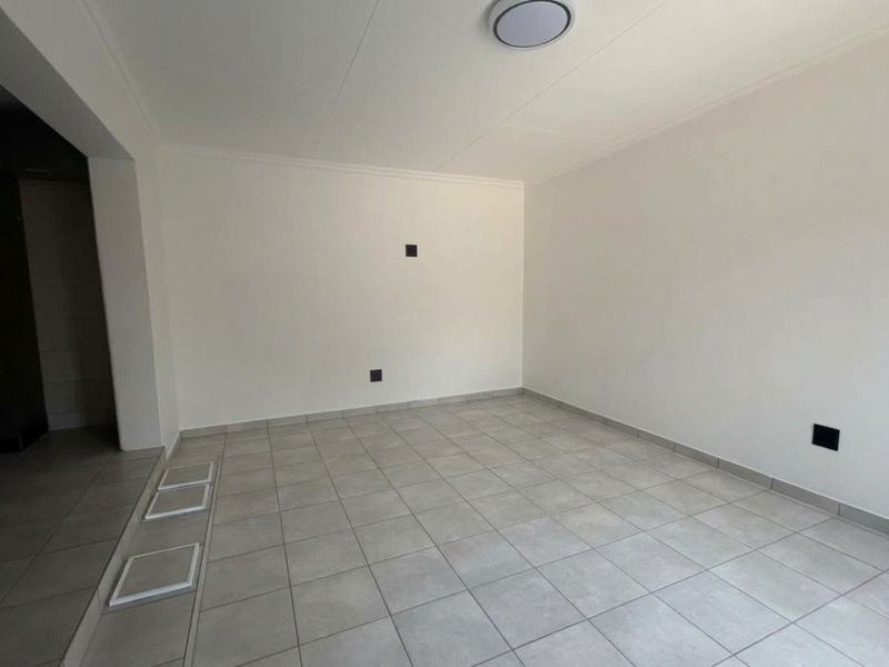 A clean, empty living area featuring neutral tiled flooring and white walls, providing a versatile blank canvas for interior design.