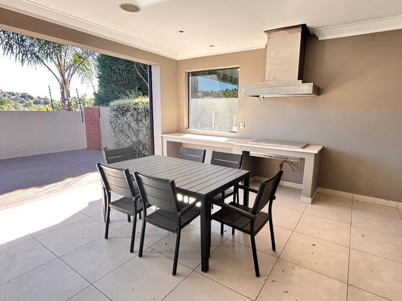 Covered patio featuring a built-in braai with stainless steel extractor hood, tiled flooring, and recessed lighting, perfect for outdoor entertaining.