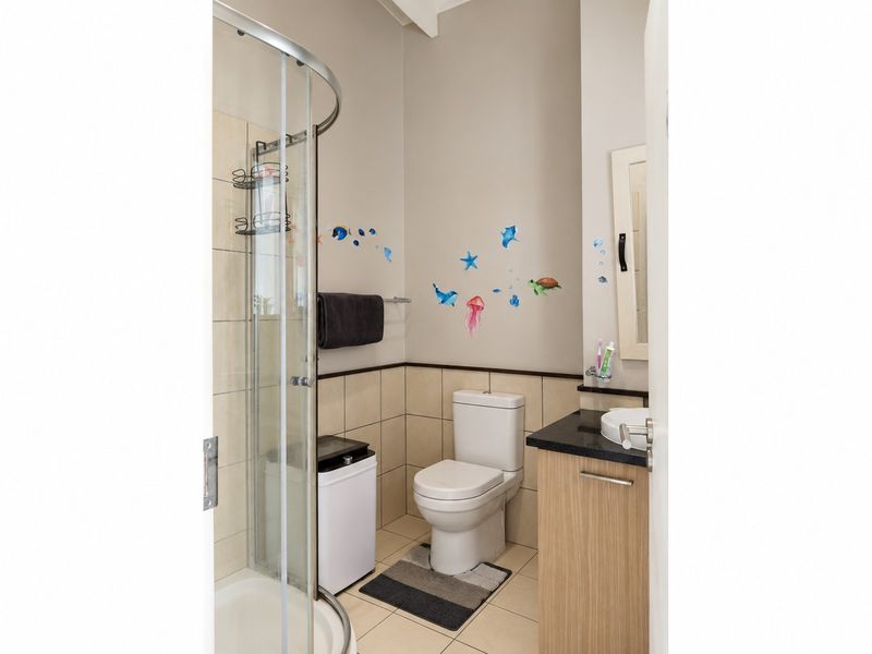 A compact bathroom featuring a shower enclosure, a modern toilet, and a vanity cabinet with a basin.