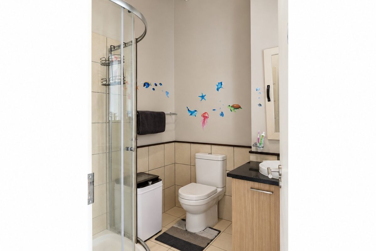 A compact bathroom featuring a shower enclosure, a modern toilet, and a vanity cabinet with a basin.