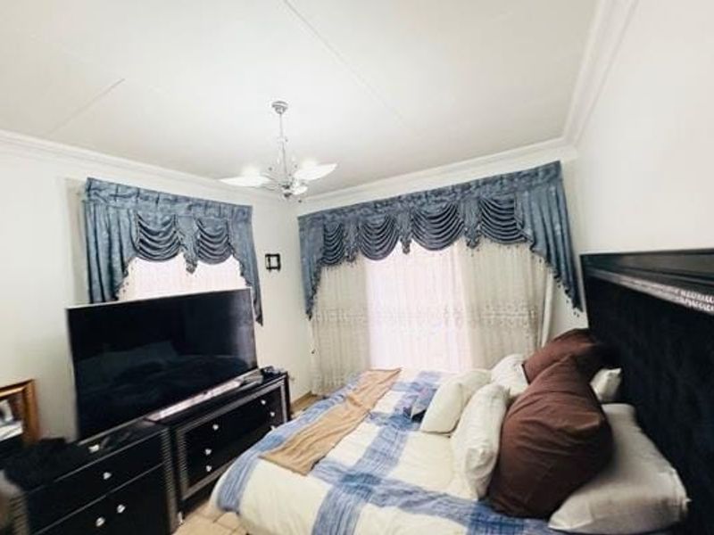 A bedroom featuring decorative ceiling cornicing and a central chandelier, providing a classic foundation for interior updates.
