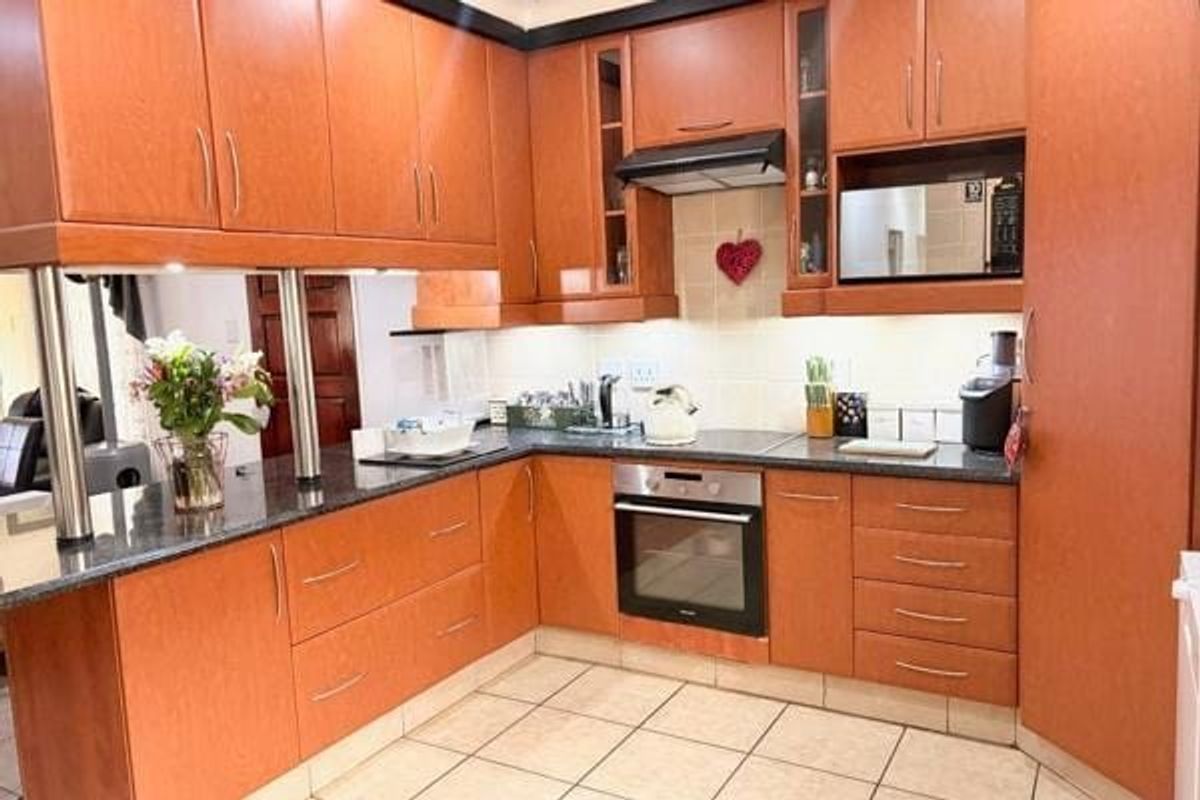 A functional kitchen featuring warm-toned wooden cabinetry, granite countertops, integrated oven, and a tiled backsplash, offering a practical layout for daily cooking.