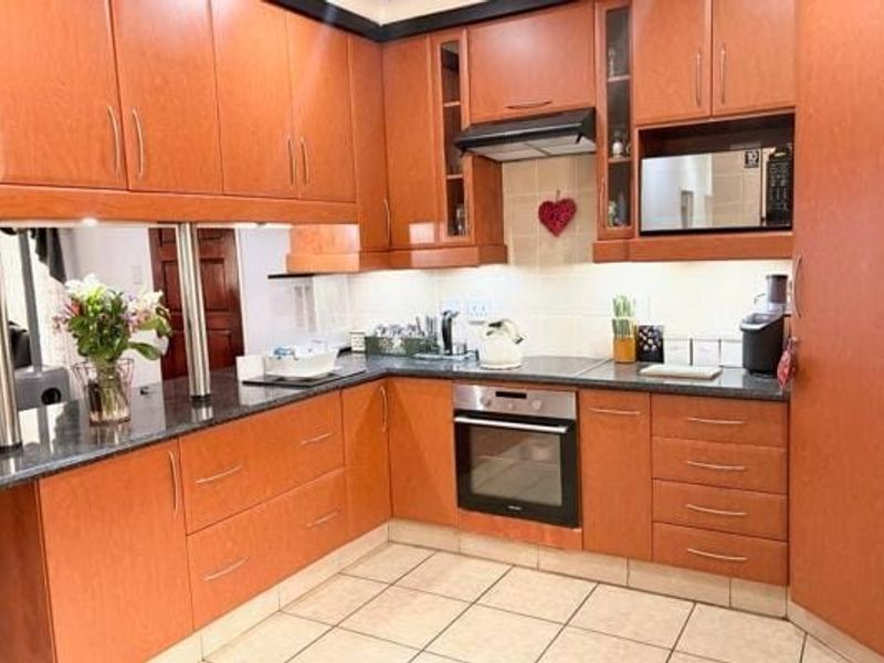 A functional kitchen featuring warm-toned wooden cabinetry, granite countertops, integrated oven, and a tiled backsplash, offering a practical layout for daily cooking.