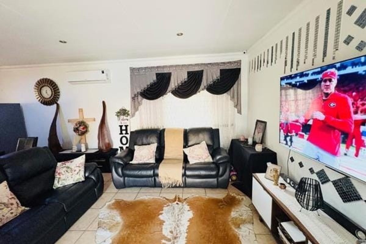 A comfortable living room featuring tiled flooring, recessed downlighting, and a wall-mounted split-system air conditioning unit.