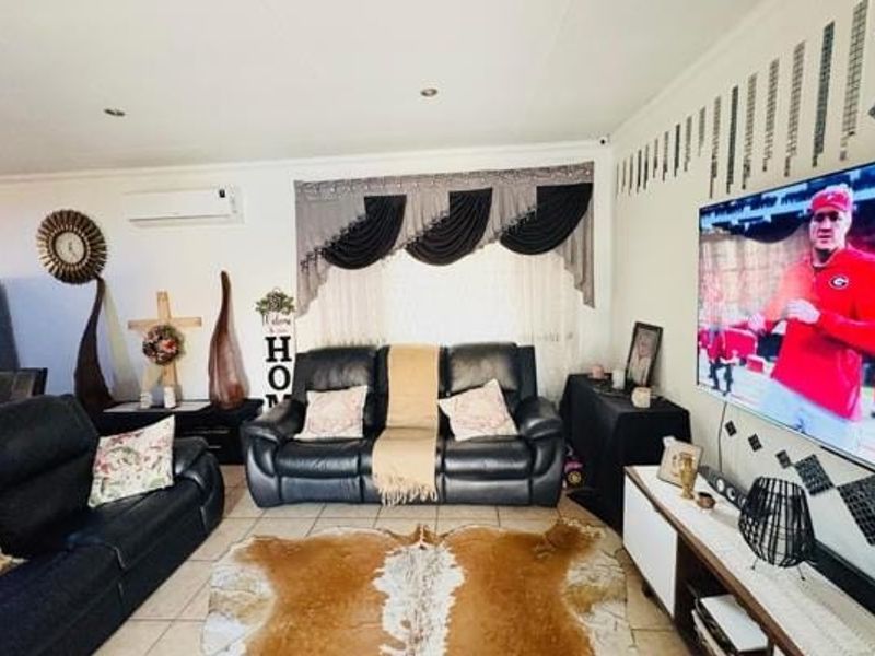 A comfortable living room featuring tiled flooring, recessed downlighting, and a wall-mounted split-system air conditioning unit.