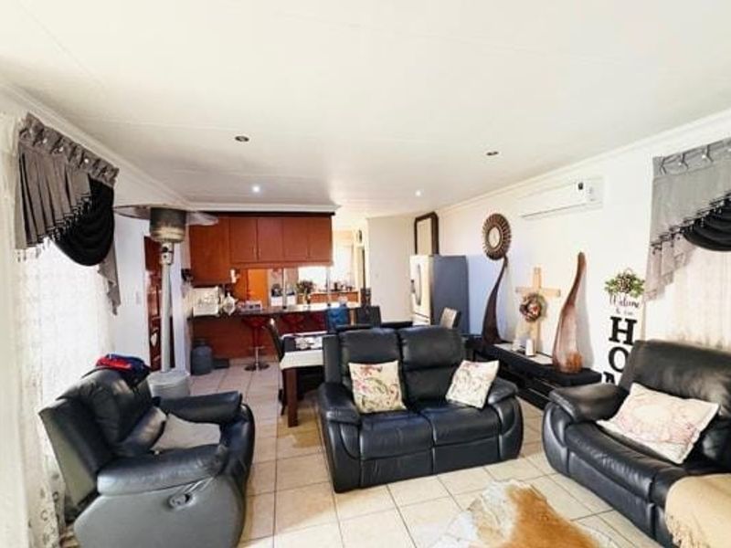 Open-plan living and kitchen area featuring tiled flooring, recessed lighting, and a split-system air conditioner, providing a functional and connected living space.