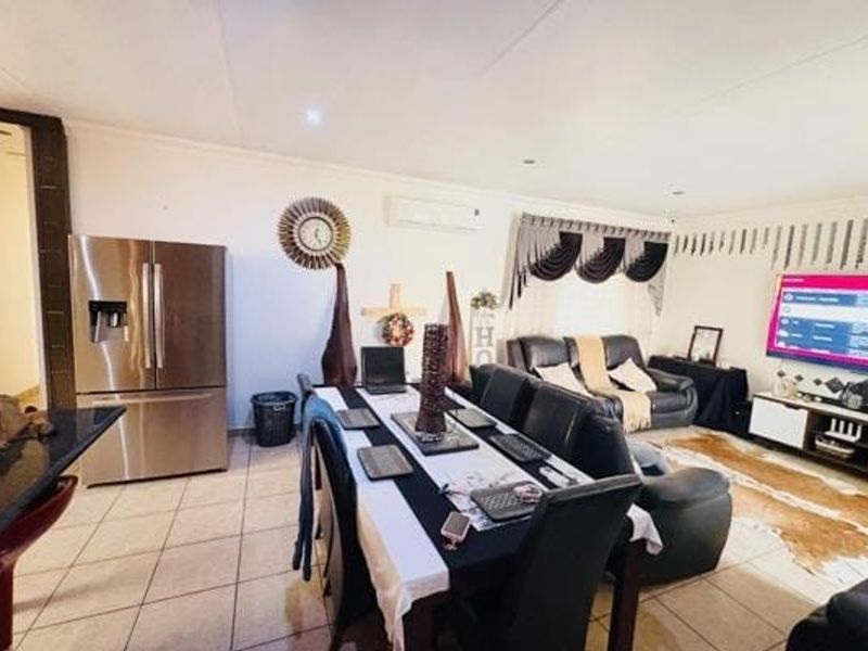 Open-plan living and dining area featuring tiled flooring, recessed lighting, and a wall-mounted air conditioning unit.