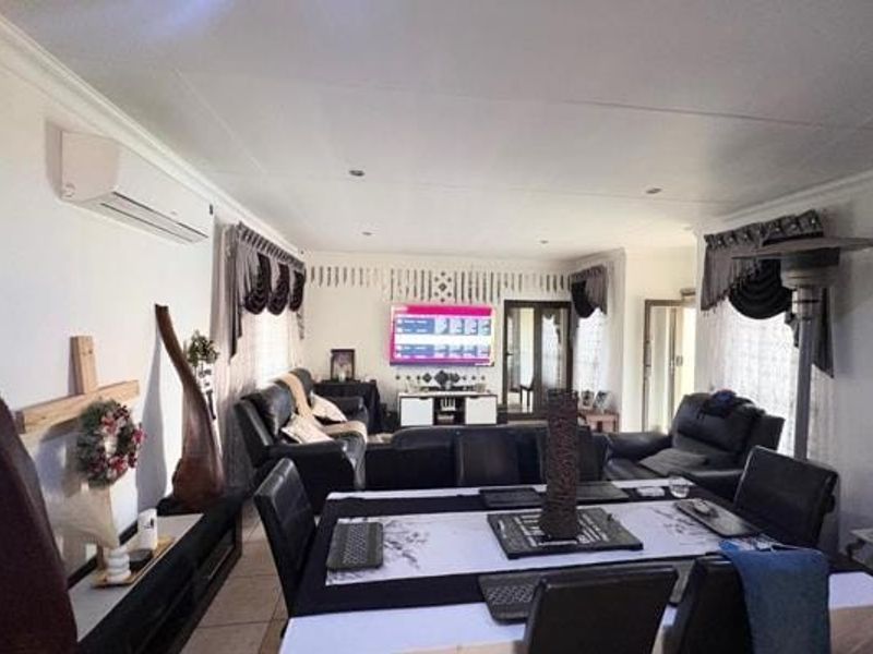 Spacious open-plan living and dining area featuring tiled flooring, recessed downlighting, and a wall-mounted split-system air conditioning unit.