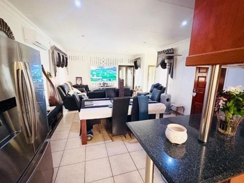 Spacious open-plan living and dining area featuring tiled flooring, recessed lighting, and a functional kitchen with granite countertops.