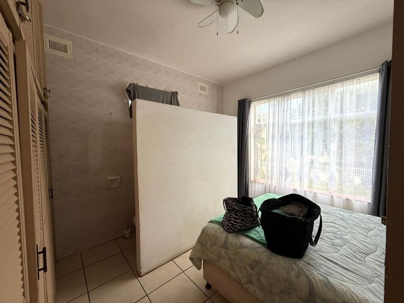 Bedroom featuring built-in cupboards, tiled flooring, and a partition wall separating the sleeping area from a small utility space.