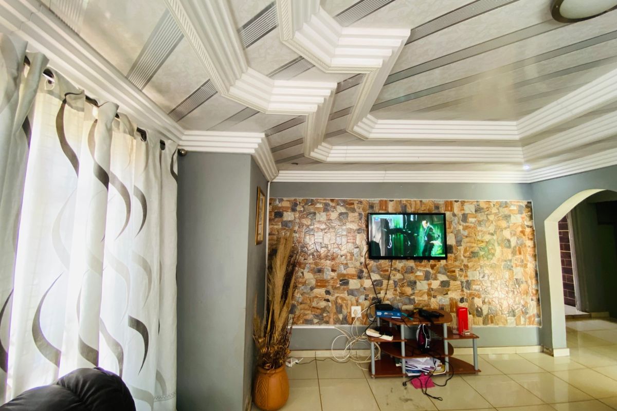 Living room featuring a decorative coffered ceiling, stone-clad feature wall, and ceramic floor tiles.